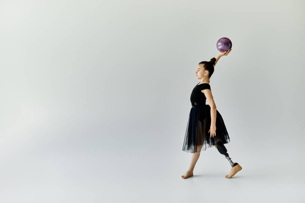 Une jeune fille avec une jambe prothétique effectue une gracieuse routine de gymnastique, montrant sa force et sa détermination. - Photo, image