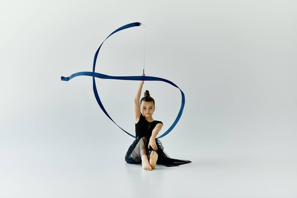 Młoda dziewczyna z protezą nogi wykonuje gimnastykę z niebieską wstążką. - Zdjęcie, obraz