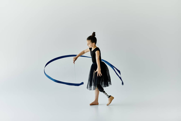 Молода дівчина з протезною ногою виконує витончену стрічку під час гімнастичної практики. - Фото, зображення
