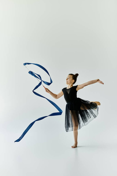 Młoda dziewczyna z protezą nogi wykonuje pełną wdzięku gimnastykę ze wstążką. - Zdjęcie, obraz