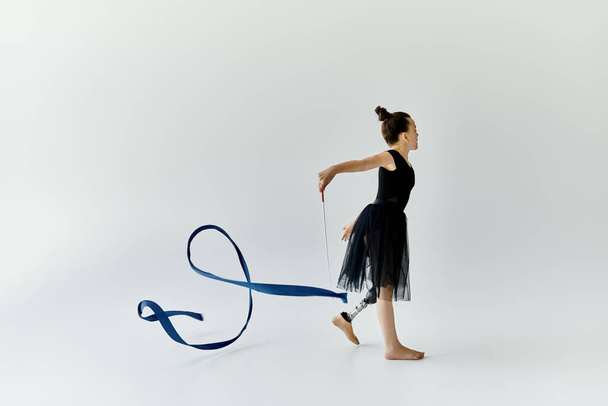Молода дівчина з протезною ногою виконує витончену гімнастичну рутину зі стрічкою. - Фото, зображення