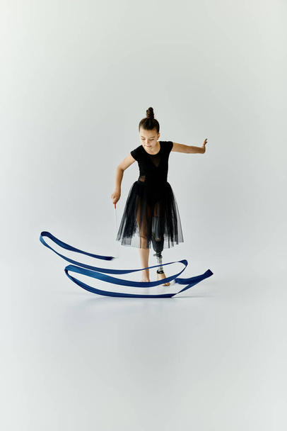 Une jeune fille avec une jambe prothétique effectue une routine de gymnastique gracieuse avec un ruban bleu. - Photo, image
