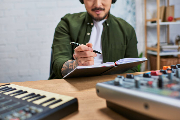 Un uomo asiatico che indossa abiti casual lavora su un nuovo pezzo musicale in uno studio di registrazione. - Foto, immagini