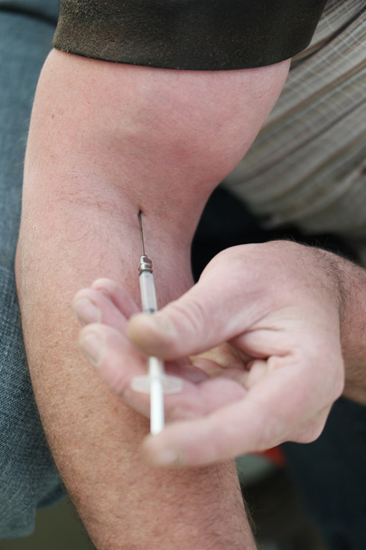 Hombre inyectándose a sí mismo con una pequeña hipodérmica
 - Foto, Imagen