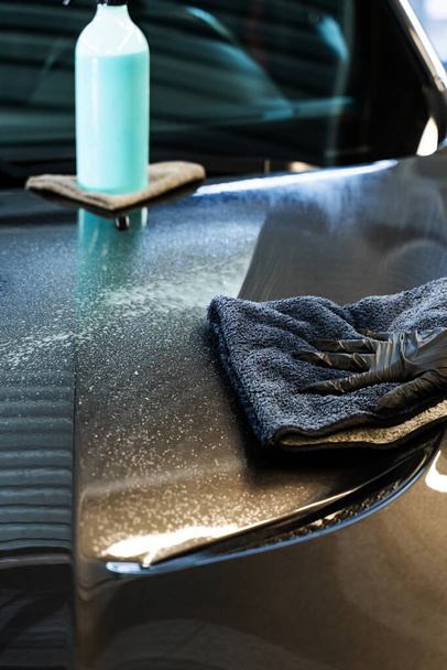 Araba yüzeyine hızlı bir temizlik spreyi sıkmak ve mikrofiber bez ile cilalamak. Araba servisinde araba temizleme işlemi - Fotoğraf, Görsel