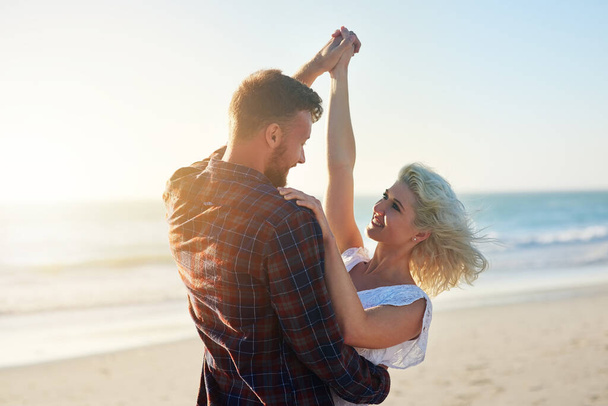 Love, smile and couple dance at beach on holiday, travel or summer vacation outdoor in nature. Romance, man and woman holding hands at sea together for connection, support and celebration at ocean. - Photo, Image