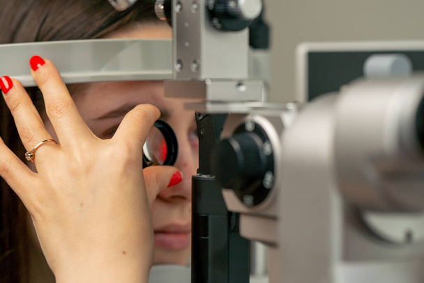 Nahaufnahme in einer Augenklinik: Junge Ärztin diagnostiziert ein junges Mädchen mit einer Lupe - Foto, Bild