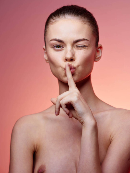 Спокойная и чувственная молодая женщина делает тихий жест с указательным пальцем на губах - Фото, изображение