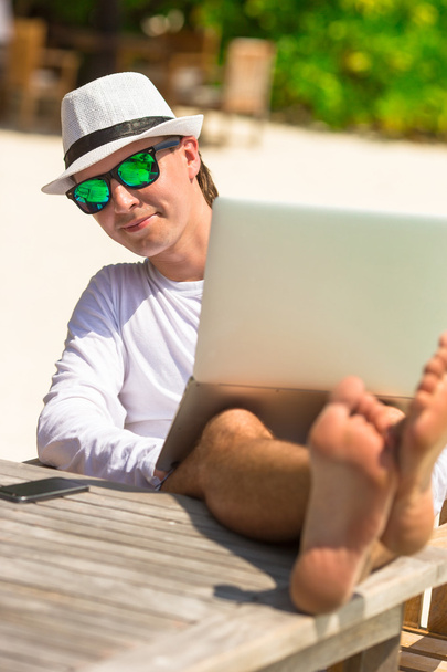 熱帯のビーチの休暇中にタブレットコンピュータを持つ若い男 - 写真・画像