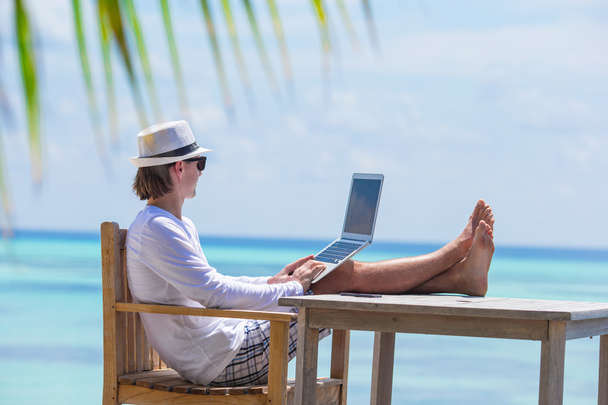 Hombre joven con tableta durante las vacaciones en la playa tropical - Foto, imagen