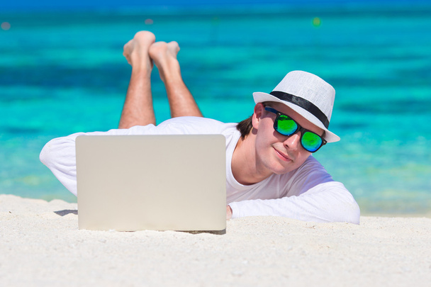 junger Mann mit Laptop am tropischen Strand - Foto, Bild