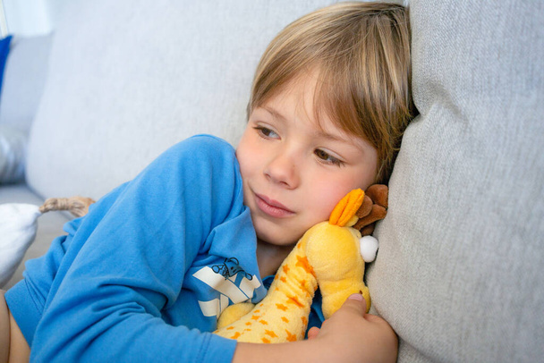 Sevimli 5 yaşındaki çocuk uyumaya hazır. Çocuk baykuşun yumuşak oyuncağına sarılıyor ve gülümsüyor.. - Fotoğraf, Görsel