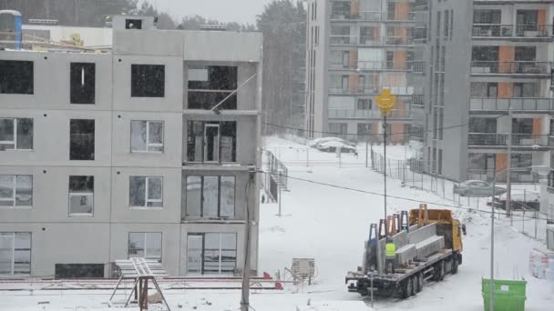Winter blizzard en werknemers met kraan lift blok huis deel - Video