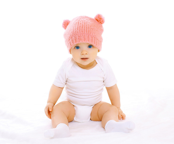 Retrato de bebé dulce sentado en el sombrero de punto rosa
 - Foto, imagen