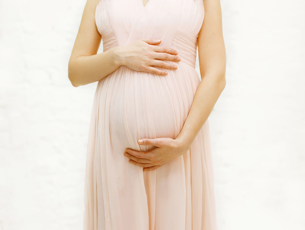 Mooie zwangere jonge vrouw in zachte jurk close-up - Foto, afbeelding