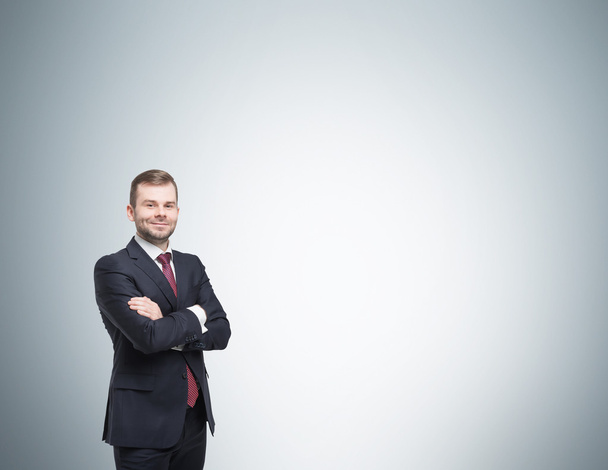 Smiling handsome businessman in a black suit with the fold arms. Studio background. - Fotografie, Obrázek