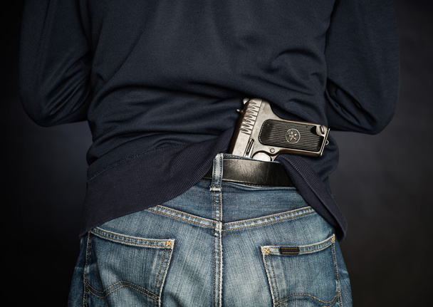 Hided handgun under the denim belt. - Fotó, kép