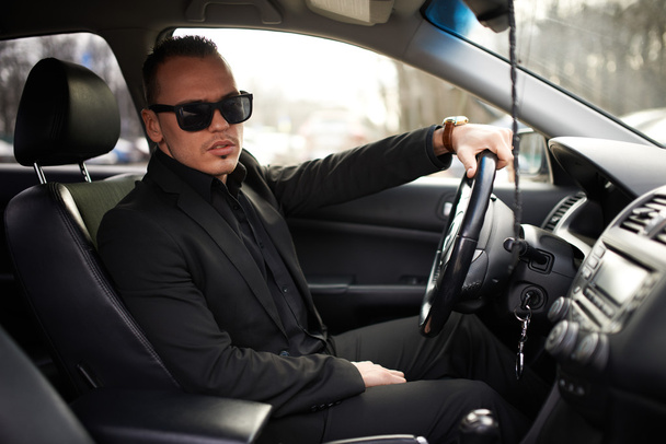 man in  black suit sitting behind the wheel - 写真・画像