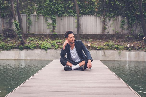 Handsome Asian model posing by an artificial basin - Photo, image