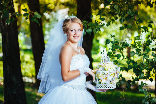 Beautiful bride posing outdoor at the park in her wedding day - Фото, изображение