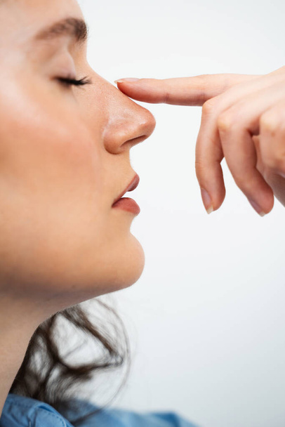 Ринопластика, чтобы изменить форму носа и улучшить дыхание. Привлекательная девушка касается носа перед септопластикой - Фото, изображение