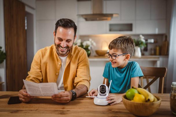Padre e hijo caucásico en casa cocina conectar e instalar cctv cámara de seguridad de vigilancia - Foto, Imagen
