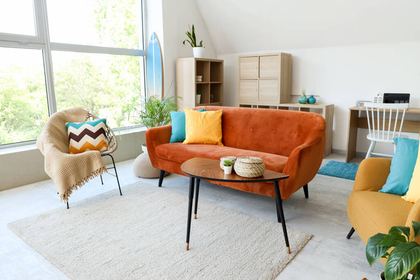 Comodo divano, tavolo, poltrona e tavola da surf all'interno del soggiorno - Foto, immagini