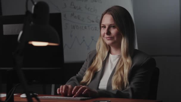 Mladá usměvavá blondýnka podnikatel sedí na pracovišti u stolu, používá počítač, provádí obchodní korespondenci on-line, zvažuje text a napíše zprávu na klávesnici. The concept of - Záběry, video