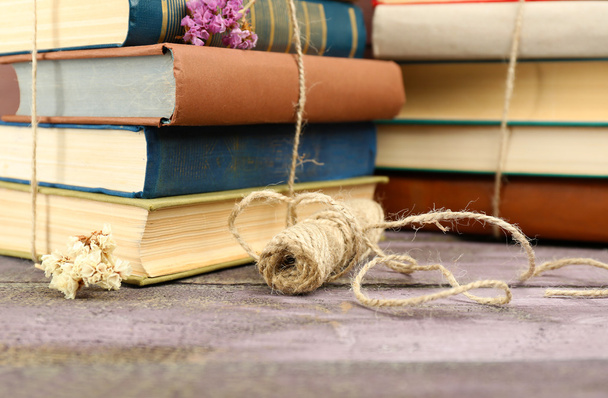 Stacks of books with dry flowers and twine on table close up - Фото, изображение