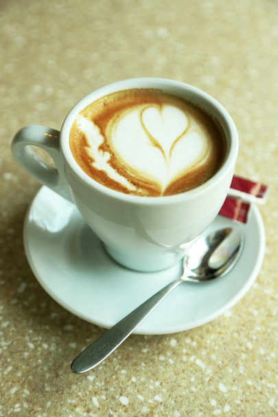 Чашка капучино з серцем на піні на столі в кафе
 - Фото, зображення