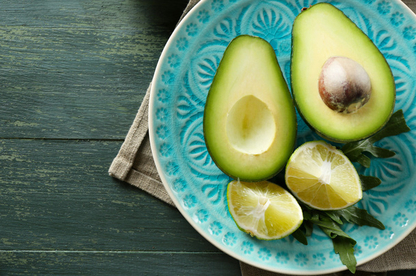 Sliced avocado and lemon lime on wooden background - Foto, afbeelding