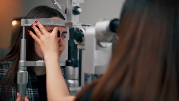 Nahaufnahme in einer Augenklinik: Junge Ärztin diagnostiziert ein junges Mädchen mit einer Lupe - Filmmaterial, Video