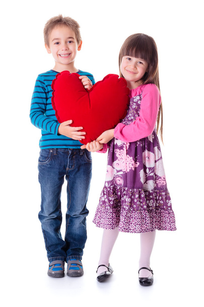 Girl and boy holding a big red heart shaped pillow - Фото, изображение