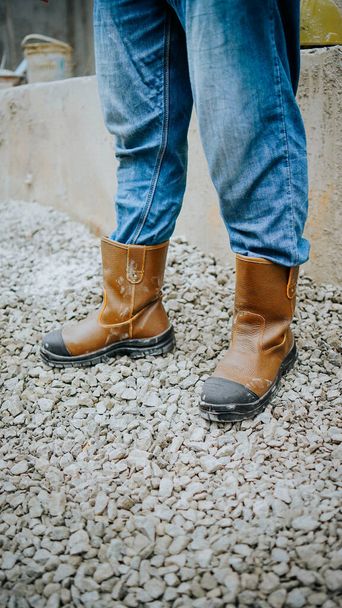 Fotografie bezpečnostních bot z hnědé kůže, které nosí stavební dělník, aby chránil své nohy před pracovními úrazy - Fotografie, Obrázek