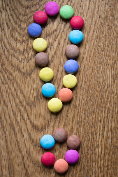 exclamation mark made of coloful praline on wooden background - Foto, Imagen