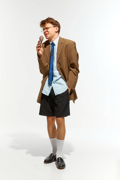 Full length πορτρέτο του άνδρα ντυμένο ρετρό ρούχα με γυαλιά τραγουδά στο μικρόφωνο σε λευκό φόντο στούντιο. Έννοια της μουσικής, φεστιβάλ, σύγχρονη τέχνη, χόμπι, δημιουργικότητα. ΠΑΡΑΡΤΗΜΑ II - Φωτογραφία, εικόνα