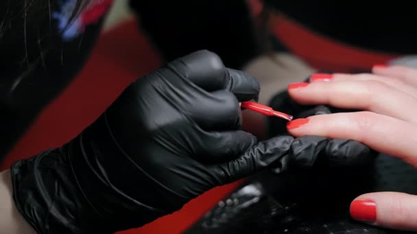 Крупный план маникюра, использующего красный лак для ногтей. Специалист по ногтям в перчатках с красным лаком для ногтей - Кадры, видео