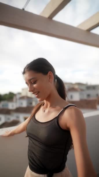 Egy fiatal nő fekete felső és világos szoknya élvezi a szabadban egy napsütéses napon az erkélyről. - Felvétel, videó
