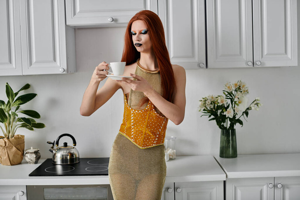 Дреґ-діва насолоджується чашкою чаю в стильній обстановці кухні. - Фото, зображення