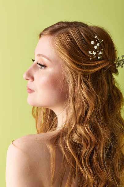 Une jeune femme en tenue blanche, avec des accents floraux dans les cheveux, regarde au loin le jour de son mariage. - Photo, image
