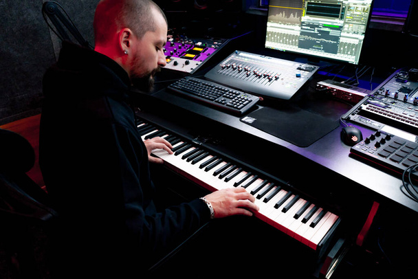in de opnameruimte donkere studio geluidstechnicus, terwijl het afspelen van platen het geluid van synthesizer selecteren van de gewenste sleutel - Foto, afbeelding