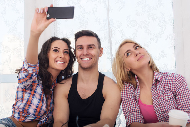 Boldog meg két nő és ember vesz fényképezőgép vagy smartphone együtt visel nyári ruhák farmer rövidnadrág jeanswear utcai városi stílusú alkalmi szórakozás selfie. - Fotó, kép