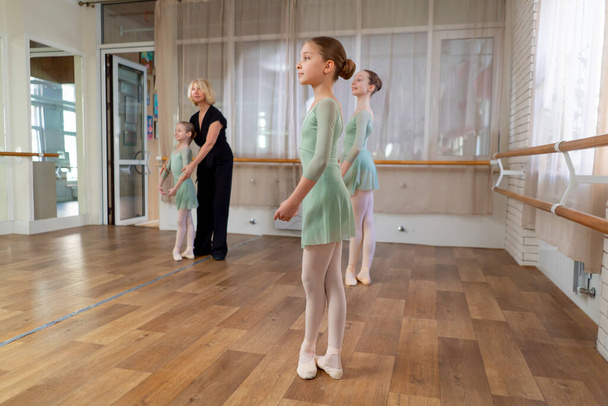 professional ballet school for children girls in a green bodysuit with a trainer training at the barre - Photo, Image