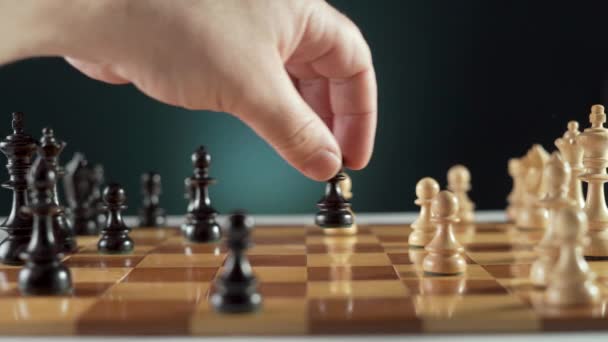 Marcos de primer plano de la mano moviendo pieza de ajedrez negro en el tablero contra el fondo. Juego de ajedrez en acción. - Imágenes, Vídeo