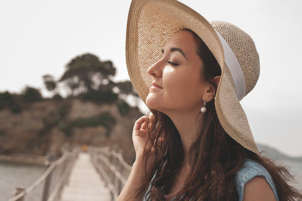 Young woman with summer hat posing on the bridge - Fotografie, Obrázek