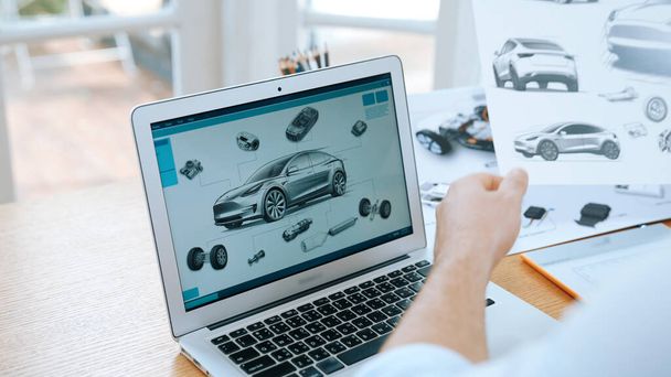 Μηχανικός σχεδιασμού αυτοκινήτων αναλύει το πρότυπο αυτοκινήτων για τις επιχειρήσεις αυτοκινήτων στο εσωτερικό γραφείο. Αυτοκίνητος μηχανικός σχεδιαστής αναλύει προσεκτικά, βρίσκοντας τα ελαττώματα και τη βελτίωση για το σχεδιασμό αυτοκινήτων με το lap-top Synchronos - Φωτογραφία, εικόνα