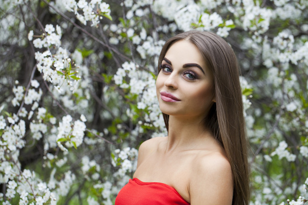 Portrait of a beautiful young girl in red dress on the backgroun - Foto, Bild