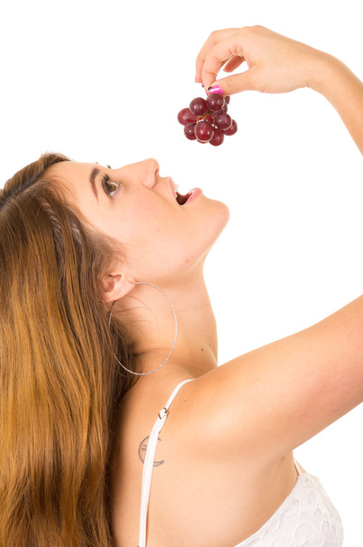 Beautiful young supersticious woman eating grapes - Foto, Imagen