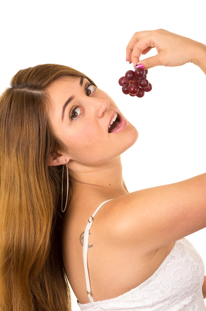 Beautiful young supersticious woman eating grapes - Photo, image