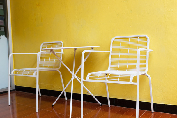 біле крісло і стіл з жовтою стіною
 - Фото, зображення